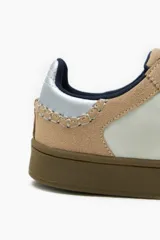 Zapatillas deportivas bajas color beige y blanco, con cordones y suela marrón.