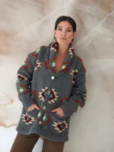Saco de lana marrón con diseño geométrico multicolor, cuello con solapa, cierre frontal con botones y bolsillos delanteros.