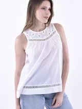 Blusa blanca sin mangas con cuello redondo y detalles calados en el frente y ruedo.