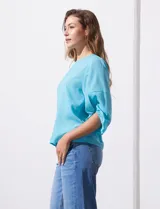 Blusa de gasa color blanco con estampado de hojas verdes, de mangas 3/4 abullonadas con puños elásticos.