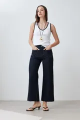 Musculosa blanca de algodón con cuello redondo y ribete negro en cuello y sisas.