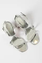 Sandalias plateadas de tacón bloque con tiras finas y cierre con hebilla en el tobillo.