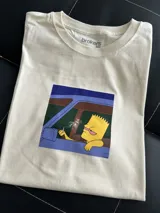 Remera oversize de algodón con estampado de Bart Simpson, mostrando expresión cansada y ojos rojos.