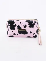 Neceser rectangular con estampado de manchas de vaca en tonos rosa y negro, cierre superior con cremallera dorada y correa de muñeca extraíble.