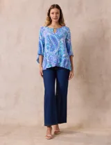 Blusa de gasa estampada con motivos paisley en tonos azules, marca Ruby Rd. Tiene cuello redondo con escote en V y aplique metálico. Presenta una sobre capa delantera y terminación asimétrica. Las mangas son 3/4 y amplias.
