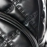 Mochila negra de cuero sintético con diseño acolchado en forma de rombos. Tiene un asa corta superior y dos correas traseras regulables. Cuenta con cierre principal, dos bolsillos externos con cierre, dos bolsillos laterales abiertos, un bolsillo interno con cierre y dos bolsillos internos abiertos.