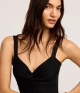 Top cropped blanco de tirantes anchos, confeccionado en tejido de punto texturizado, con escote en V y detalle de nudo o torcido en el centro del busto.