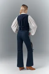 Pantalón de jean de tiro medio, calce ajustado, lavado azul oscuro, pierna levemente acampanada con ruedo ancho.