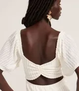 Vestido largo blanco de tejido laise con textura plisada vertical, escote cuadrado y mangas cortas con volado.