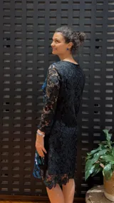 Vestido negro de manga larga, confeccionado en guipur bordado con flores azules y blancas.