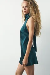 Vestido corto color verde esmeralda de satén con cuello halter y espalda descubierta con lazada.