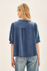Camisa celeste de algodón con apliques de encaje a tono en pechera y mangas. Cierra con botones de pasta a tono en el frente. Puños con elásticos que generan efecto balloon.