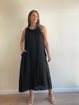 Vestido largo de lino color celeste, sin mangas y con cuello buche. Presenta un diseño de corte holgado con bolsillos laterales.