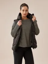 Chaleco puffer color borgoña con capucha, cierre frontal con botones a presión y bolsillos laterales. Diseño acolchado y corte recto.