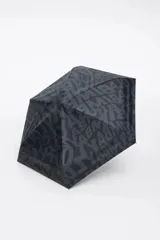 Paraguas plegable con funda cilíndrica de tela estampada con el logo de Bimba y Lola en tonos grises y negros. La base de la funda es de color fucsia y tiene un cordón de sujeción fucsia.