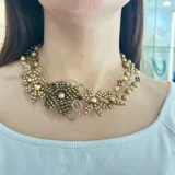 Collar dorado con diseño floral, elaborado con cuentas de diferentes tamaños y tonos de dorado.