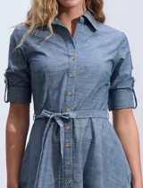 Vestido camisero blanco de algodón con cuello con solapa, delantera abotonada, mangas 3/4 regulables con presilla y botón, y cintura con lazo de ajuste.