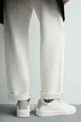 Zapatillas deportivas blancas de caña baja con detalle de color gris en el talón y suela con volumen.