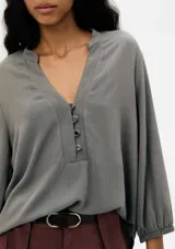 Blusa color verde claro, de mangas 3/4 con elástico en los puños, escote en V con botones y corte holgado.