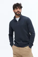 Buzo de algodón color verde musgo, con cuello alto y cierre frontal parcial. Presenta puños y cintura acanalados, y un pequeño logo bordado en el pecho.