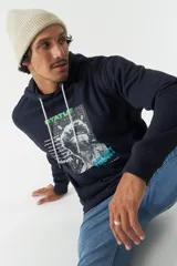 Canguro azul marino de felpa con capucha y cordones blancos. Presenta un estampado con una imagen de una escultura y texto en verde y blanco. Tiene bolsillos tipo canguro y puños y cintura acanalados.