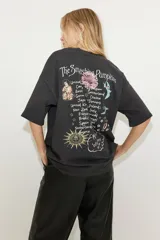 Remera negra de corte amplio con estampado del logo de la banda The Smashing Pumpkins, ángeles, flores y un sol.