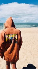 Buzo hoodie color ladrillo con estampado en la espalda de montañas y sol.