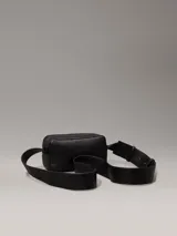 Bolso bandolera negro de Calvin Klein, confeccionado en piel sintética suave. Tiene correa ancha ajustable, cierre de cremallera, bolsillo exterior y bolsillo interior.