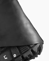 Bota negra de cuero ecológico con caña alta asimétrica y suela track con detalles metálicos.