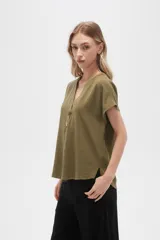 Blusa color crudo de viscosa, corte holgado, con cuello en v y cierre frontal con dos botones de madera.