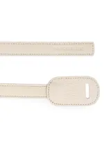 Cinturón de cuero color tostado, sin hebilla, con terminaciones redondeadas y costuras a tono.