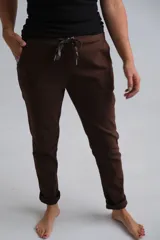 Pantalón de corte recto color chocolate, confeccionado en tela elástica. Presenta cintura con elástico y cordón ajustable con punteras metálicas, además de bolsillos laterales y ruedos con dobladillo.