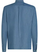 Camisa de chambray celeste de puro algodón, corte regular, con cuello abotonado, puños redondeados con dos botones y logo de Tommy Hilfiger bordado en el pecho.