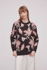 Sweater de acrílico con diseño estampado en tonos rosas y negro, de manga larga y cuello redondo.