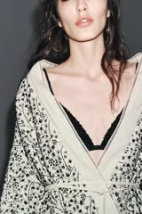 Kimono abierto color crudo con bordados florales negros y abalorios. Confeccionado en hilatura con lino y viscosa, de manga larga y cinturón ajustable con lazadas.