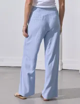 Pantalón celeste a rayas verticales, de lino, corte wide leg y tiro alto con botones decorativos.