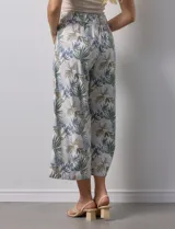 Pantalón crop de lino estampado con hojas en tonos verdes y azules. Tiene pretina trasera elastizada y bolsillos delanteros.