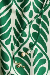 Vestido corto evasé de algodón con estampado de hojas verdes. Tiene mangas globo cortas de diseño raglán, escote redondo con cordón para ajustar y corte holgado.