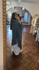 Ruana tejida a mano en color lila, confeccionada en lana merino. Presenta un diseño de punto con calados diagonales y terminación de flecos largos en el ruedo.