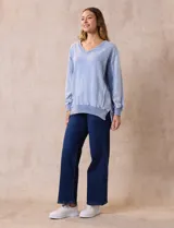 Buzo celeste de algodón con efecto lavado, escote en V, cuello, puños y ruedo acanalados y tajos laterales.