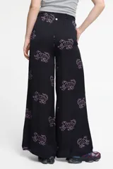 Pantalón ancho de seda viscosa color negro con estampado de tigres en color rosa. Cuenta con bolsillos laterales y elástico en la cintura.