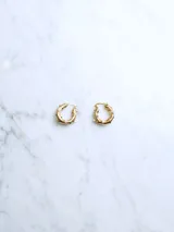 Par de aros tipo argolla dorados con textura irregular y detalles de perlas pequeñas.