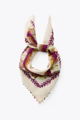 Pañuelo cuadrado de algodón color crema con estampado de flores rojas, rosadas, celestes y verdes. Tiene un borde con abalorios de colores.