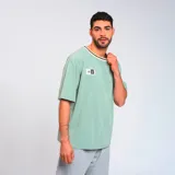 Remera verde con cuello redondo con ribete negro y beige, manga corta y parche con logo de la marca en el pecho.