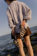 Sandalias tipo mule de cuero color marrón chocolate, con diseño de tiras anchas cruzadas y suela plana.