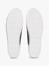 Zapatillas de lona azul oscuro con efecto lavado, corte bajo, cordones negros y suela de goma blanca. Presentan un pequeño logo esmaltado de Tommy Hilfiger en el lateral exterior.