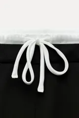 Pantalón ancho gris con textura de espiga, tiro alto, doble cintura elástica ajustable con cordón, pinzas frontales, bolsillos delanteros y falso bolsillo de vivo en la espalda.