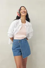 Short pollera de denim azul con corte asimétrico y cierre con botón.