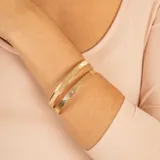 Pulsera rígida dorada con textura satinada y otra con textura martillada.