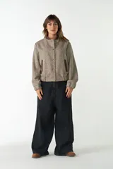 Campera bomber color gris topo, de cuello redondo y manga larga con puños elásticos. Tiene bolsillos delanteros y cierre frontal con broches.